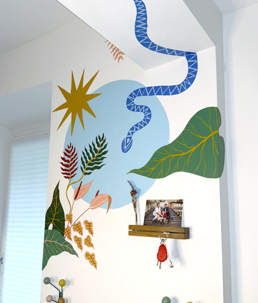Detail of a custom hand-painted botanical wall mural featuring tropical leaves, a blue snake and abstract nature-inspired shapes.